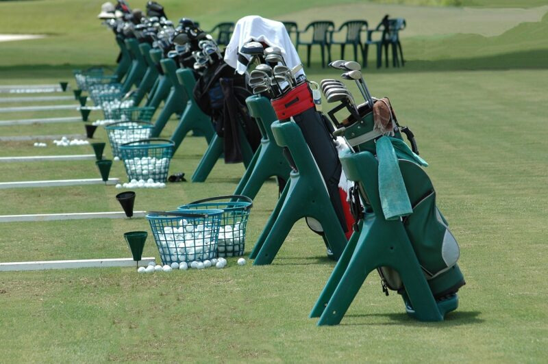 出典：O-DAN　ゴルフ練習場での場面　ゴルフクラブのセットが並んでる