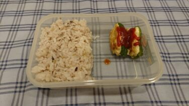 ご飯と主菜の肉詰めピーマンを入れた弁当箱