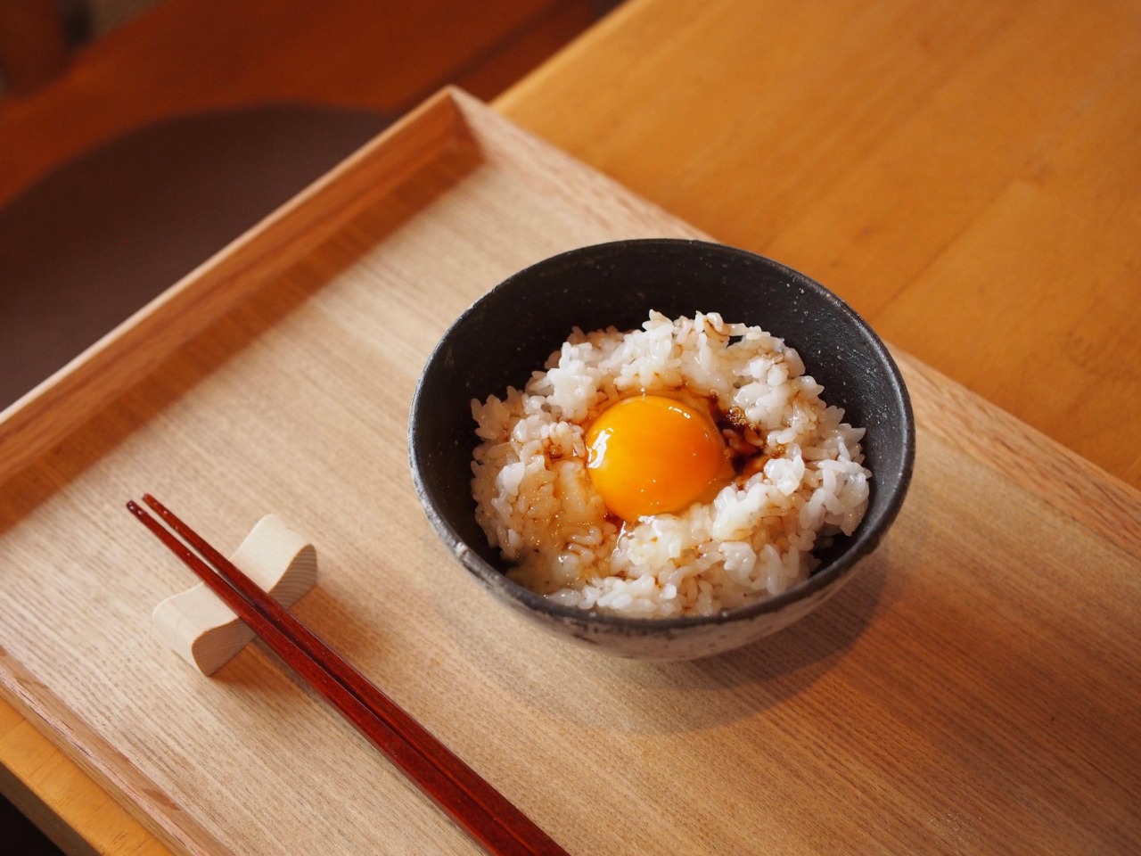 最高に美味しい。お盆の上の卵かけご飯のみが箸と一緒に置かれている素朴な画像